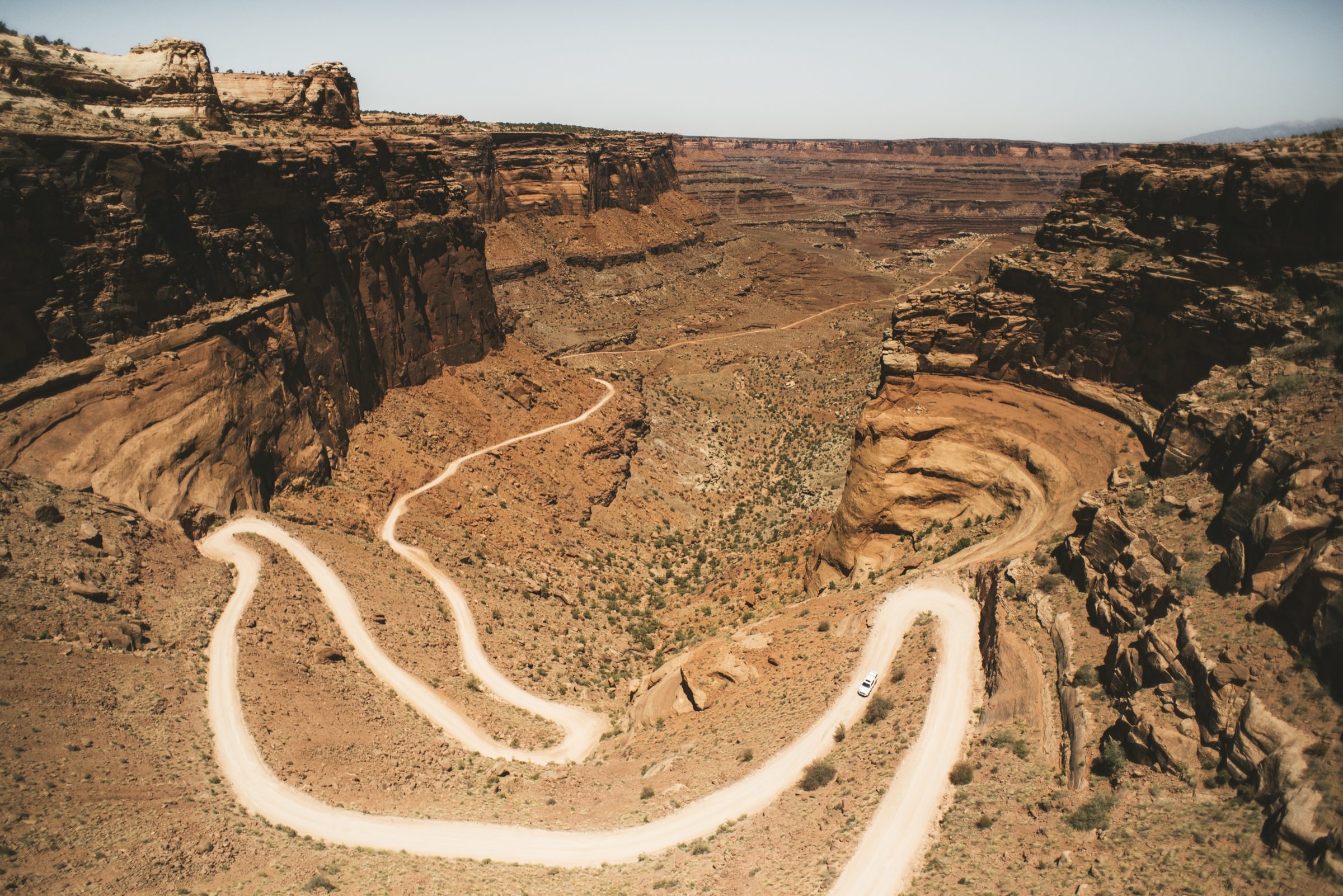 A dirt road switching back down into a red canyon